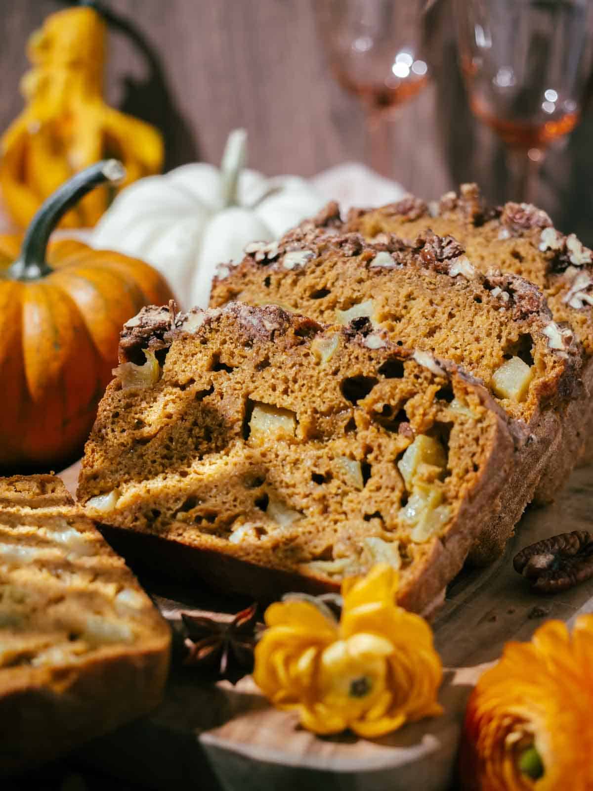 Slices of pumpkin apple bread are served on a wooden board.